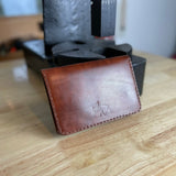 Reisepasshülle aus braun-rötlichem Leder, handgenäht für einen Reisepass, Scheckkarten oder Geldscheine, mit Logo Elch.