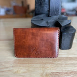 Reisepasshülle aus braun-rötlichem Leder, handgenäht für einen Reisepass, Scheckkarten oder Geldscheine, mit Logo Elch.