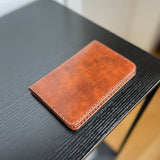 Reisepasshülle aus braun-rötlichem Leder, handgenäht für einen Reisepass, Scheckkarten oder Geldscheine, mit Logo Elch.