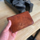 Reisepasshülle aus braun-rötlichem Leder, handgenäht für einen Reisepass, Scheckkarten oder Geldscheine, mit Logo Elch.