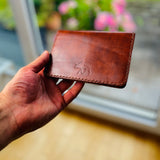 Reisepasshülle aus braun-rötlichem Leder, handgenäht für einen Reisepass, Scheckkarten oder Geldscheine, mit Logo Elch.