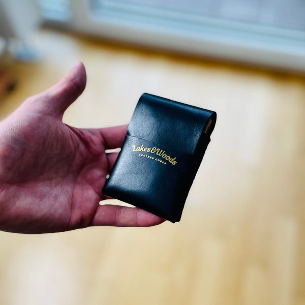 vertikaler Kartenhalter in der Farbe schwarz, handgenäht mit Logo Lakes&Woods leather goods in der Farbe Gold.
